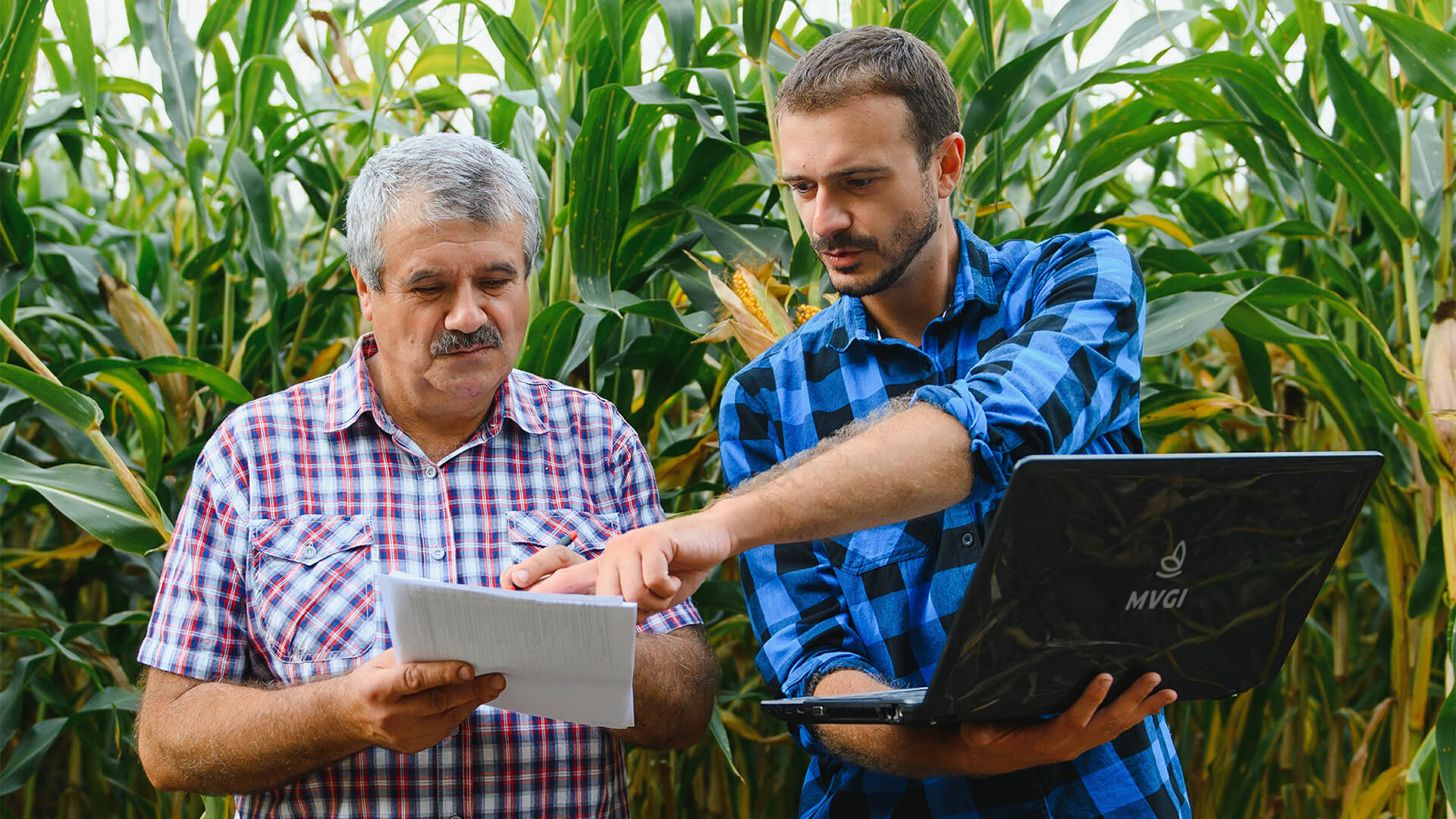 homens conversando segurando papel e laptop