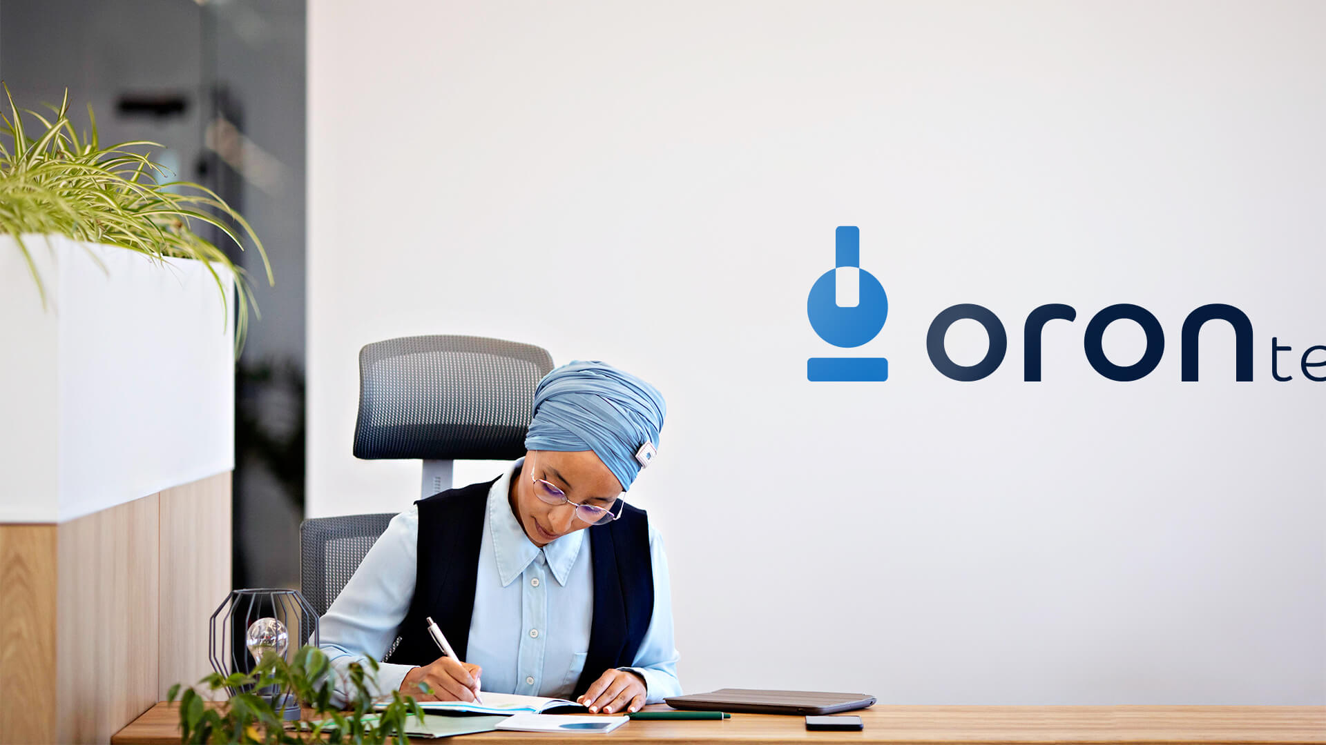 mulher negra de turbante azul sentada no escritório oron