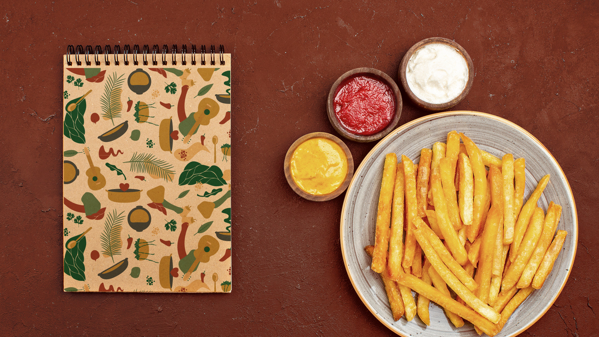 Caderneta com padronagem da marca Raízes e porção de batata frita com molhos